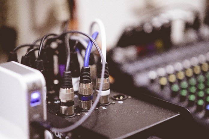 The image shows an audio equipment setup, specifically the rear connections of a mixing console or soundboard.